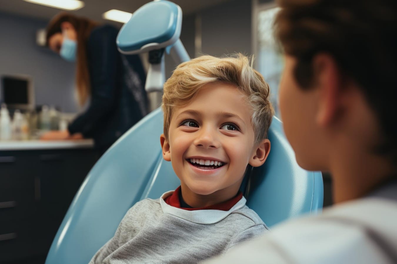 An enthusiastic blonde child with a bright smile sits comfortably in an orthodontic chair, eagerly awaiting Phase 1 treatment. The anticipation of a positive transformation shines through their joyful expression, radiating excitement for the orthodontic journey ahead.
